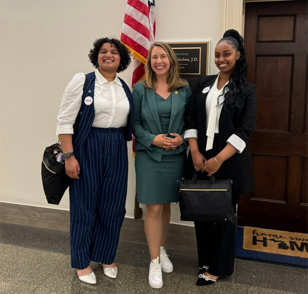 Two students stand alongside U.S. Representative